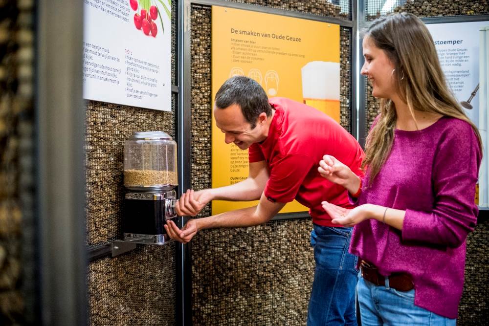 Twee jonge mensen proeven graan aan een verdeelautomaat