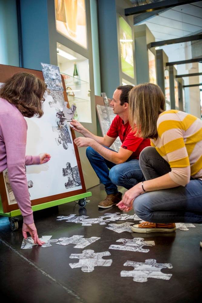 Drie mensen maken een puzzel in het bezoekerscentrum