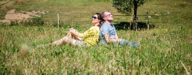 Twee mensen zitten rug aan rug in het gras